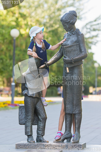 Image of The girl climbed on the monument to the first teacher