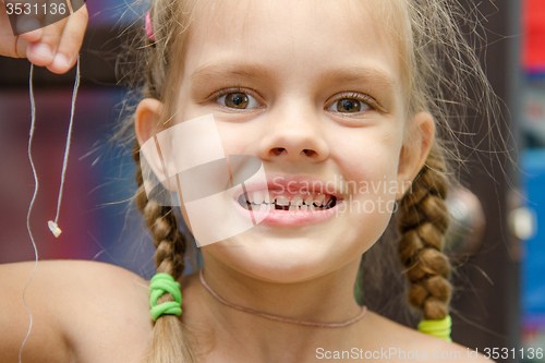 Image of Six year old girl holding her lost tooth on a string