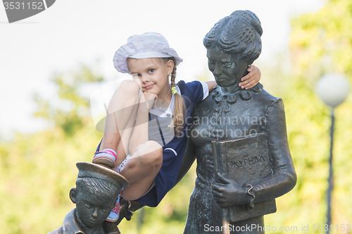 Image of Girl thoughtfully sitting on the monument to the first teacher