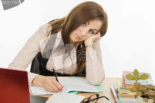 Image of Tired teacher checks students notebooks