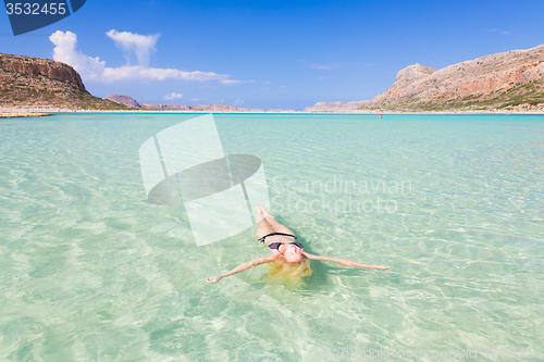 Image of Caucasian lady floating in turquoise sea.