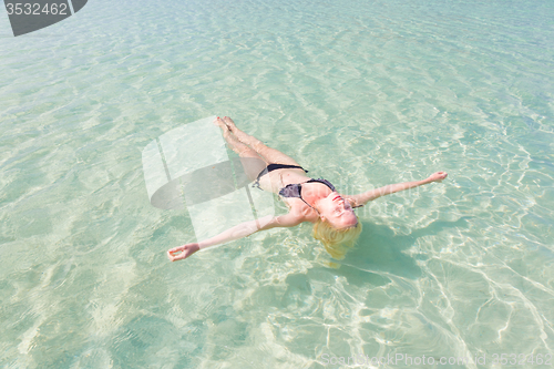 Image of Caucasian lady floating in turquoise sea.