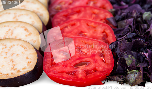 Image of Sliced eggplant tomato and basil leaves