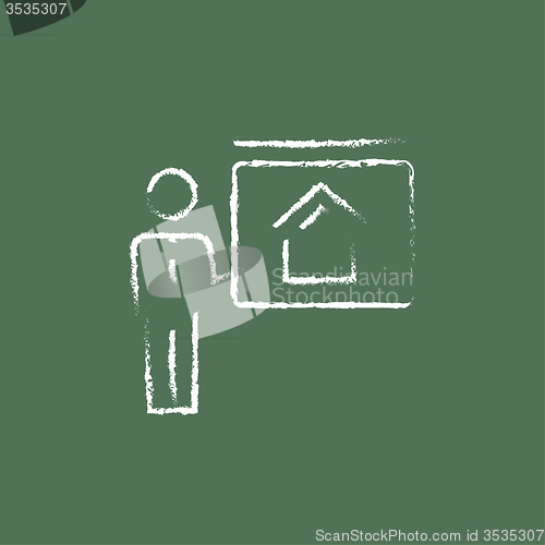 Image of Real estate agent showing the house icon drawn in chalk.