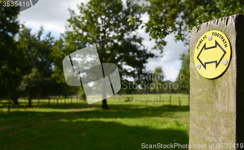 Image of Public footpath sign points into a field with trees