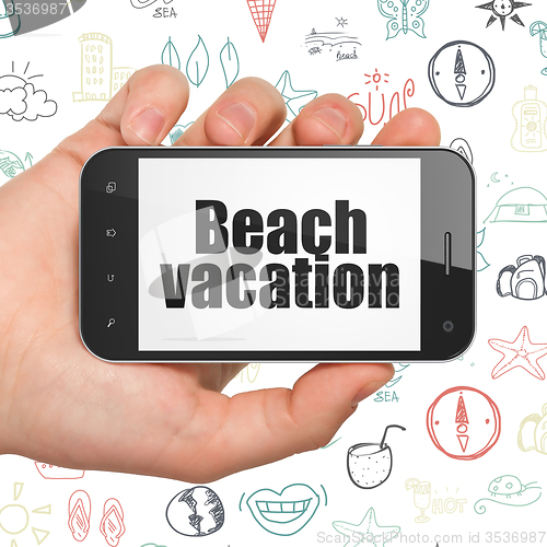 Image of Tourism concept: Hand Holding Smartphone with Beach Vacation on display