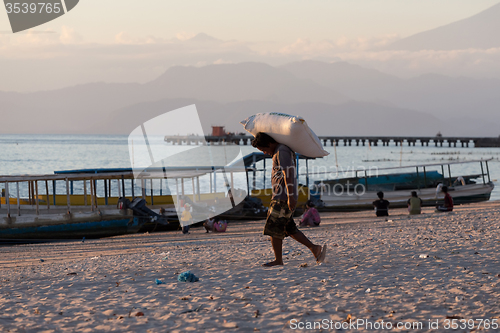 Image of Men transports cargo from ship