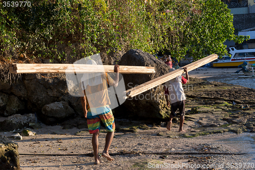 Image of Men transports cargo from ship to shipyard