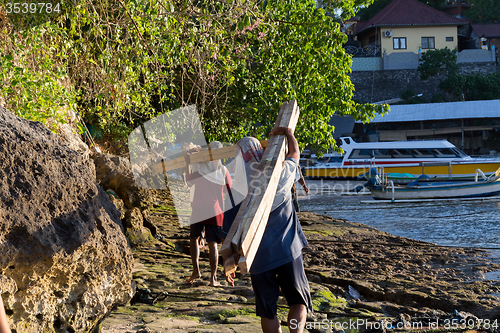 Image of Men transports cargo from ship to shipyard