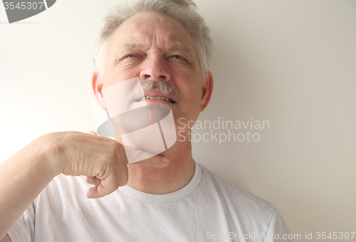 Image of Senior man gestures with finger across throat. 