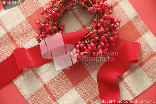 Image of Christmas berries and ribbon on plaid