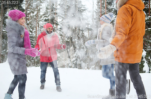 Image of happy friends playing with snow in winter forest