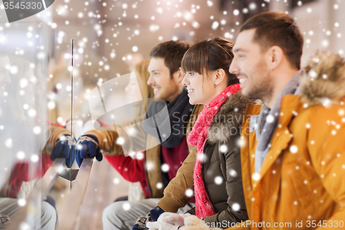 Image of happy friends watching hockey game on skating rink