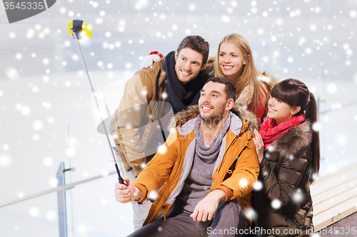 Image of happy friends with smartphone on skating rink