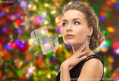 Image of beautiful woman wearing earrings over lights