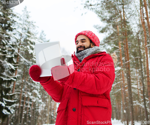 Image of happy man with tablet pc in winter forest