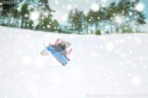 Image of happy teenage girl sliding down on snow tube