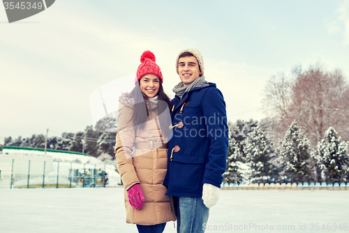 Image of happy couple ice skating on rink outdoors