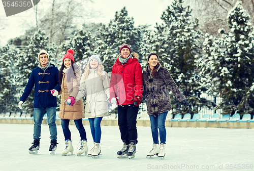 Image of happy friends ice skating on rink outdoors