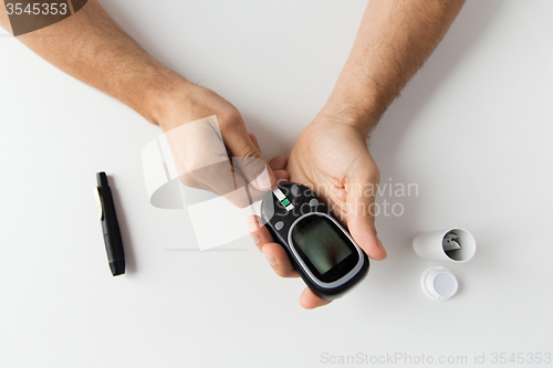 Image of close up of man checking blood sugar by glucometer