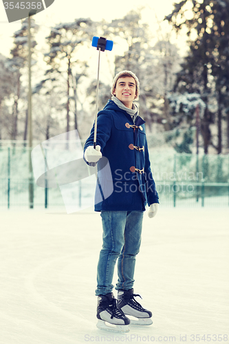 Image of happy young man with smartphone on ice rink