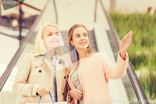 Image of young women pointing finger on escalator in mall