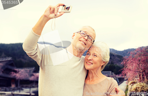 Image of senior couple with camera over asian village