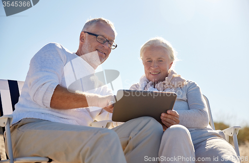 Image of happy senior couple with tablet pc on summer beach