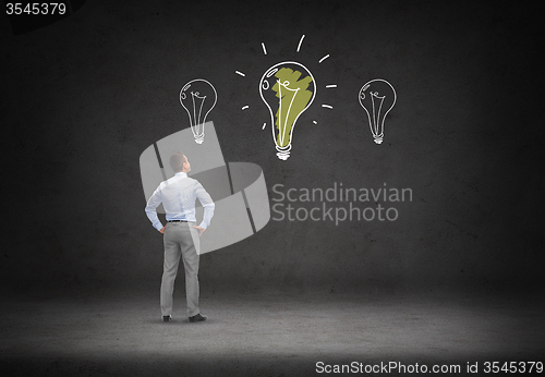 Image of businessman looking at lighting bulb doodles