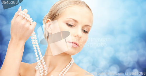 Image of beautiful woman with sea pearl necklace over blue