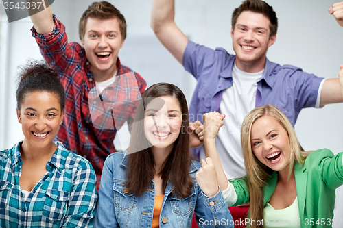 Image of group of happy students making triumph gesture