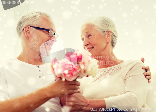 Image of happy senior couple with bunch of flowers at home