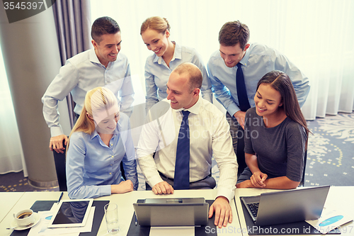 Image of smiling business people with laptop in office