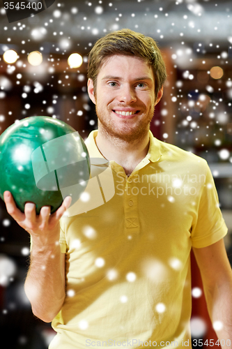 Image of happy young man holding ball in bowling club