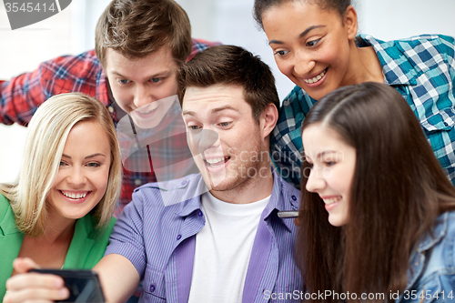 Image of group of happy students with smartphone at school