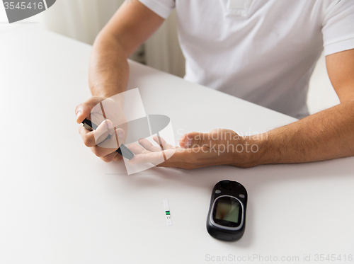 Image of close up of man checking blood sugar by glucometer