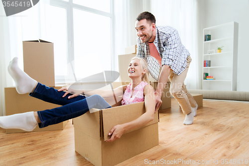 Image of couple with cardboard boxes having fun at new home