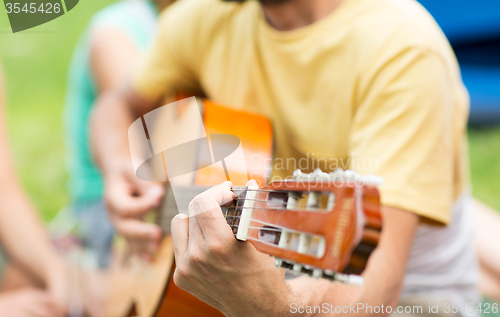 Image of close up of man playing guitar at camping