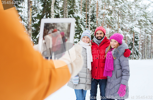 Image of smiling friends with tablet pc in winter forest