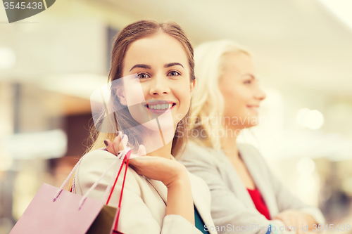 Image of happy young women with shopping bags in mall