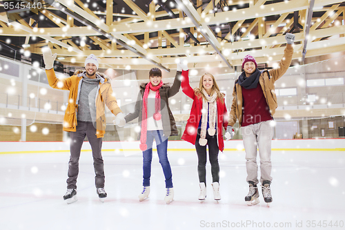 Image of happy friends waving hands on skating rink