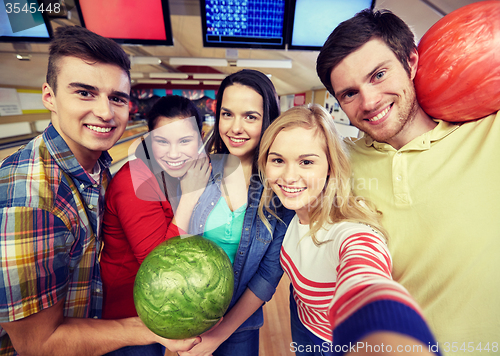 Image of happy friends taking selfie in bowling club