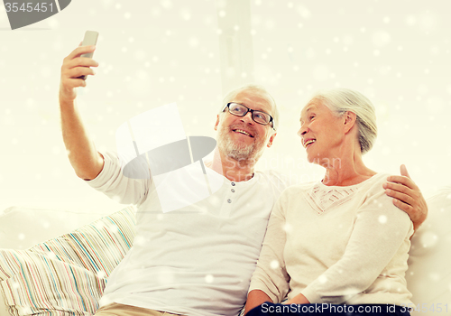 Image of happy senior couple with smartphone at home