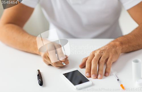 Image of close up of man with smartphone making blood test