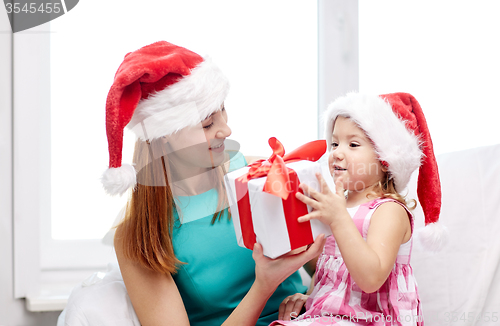 Image of happy mother and child in santa hats with gift box