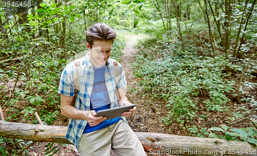 Image of happy man with backpack and tablet pc in woods