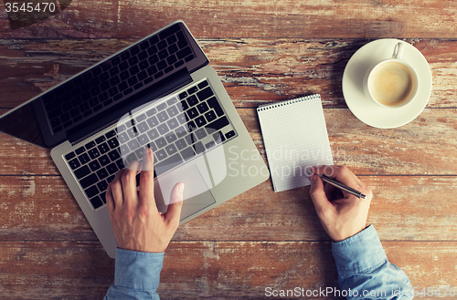 Image of close up of male hands with laptop and notebook