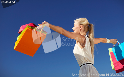 Image of smiling woman with shopping bag rising hands