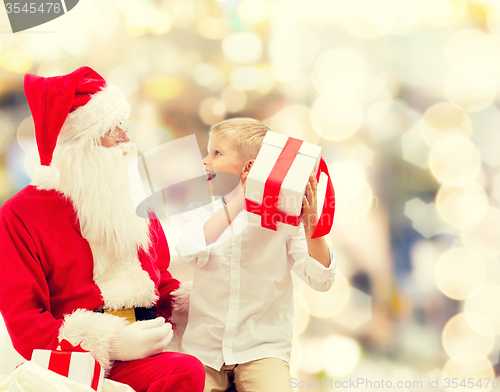 Image of smiling little boy with santa claus and gifts