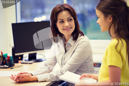 Image of school girl with notebook and teacher in classroom